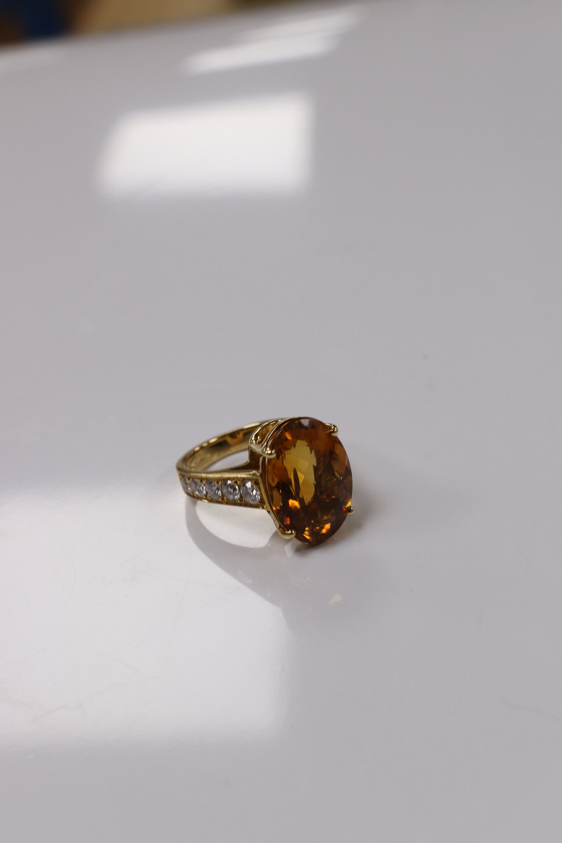 A modern 18k and single stone oval cut citrine set dress ring, with ten stone graduated diamond set shoulders, size K, gross weight 7,7 grams. Condition - good